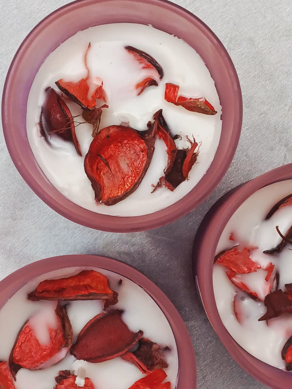Three bowls filled with a white substance and red and brown pieces on a gray surface